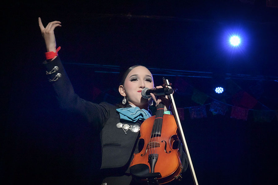 A girl holds up her arm as she sings into a mic