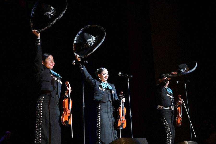 Three students hold up their sombreros during the performance