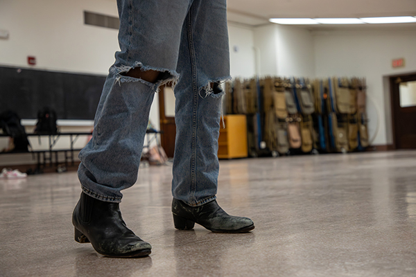 A closeup of a student's legs in ripped jeans and black boots