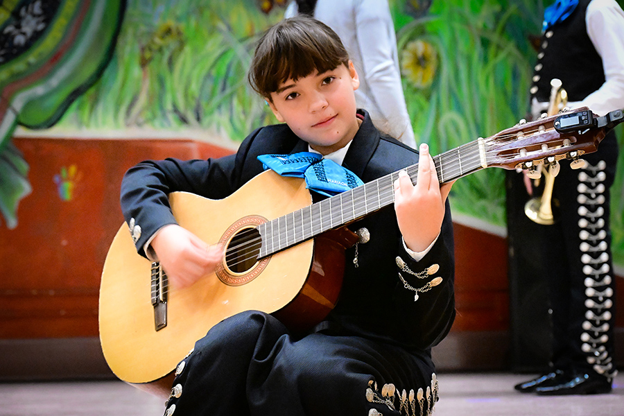 A girl sits on the floor playing guitar
