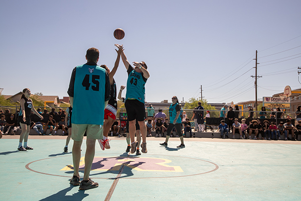 A student and teacher jump up to get the basketball