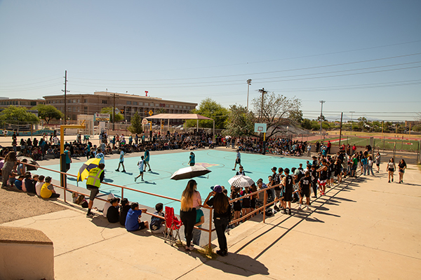 Students gather around the basketball court to watch their classmates play