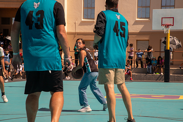 A girl looks between two teachers to see where to pass the basketball