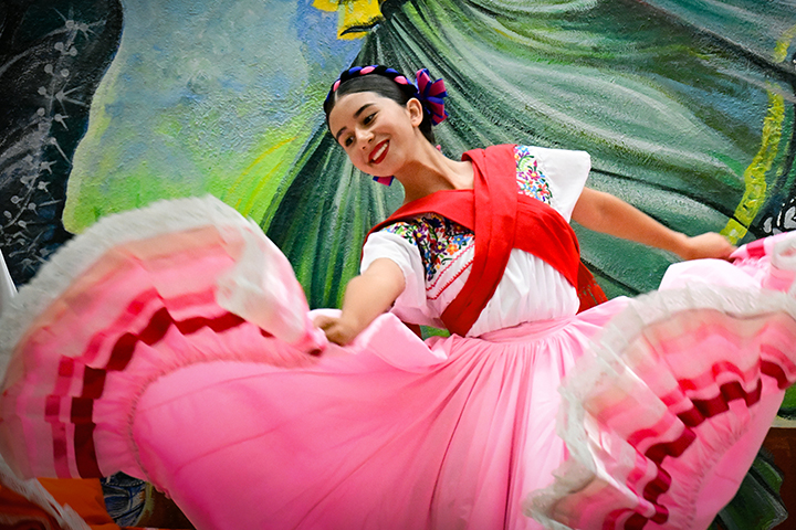 A girl twirls in her pink and red folklorico dress