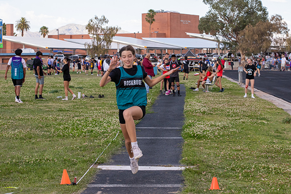 A girl runs towards the long jump sand pit