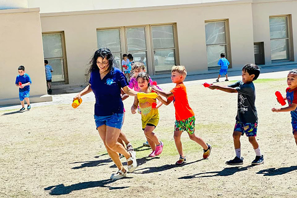 Students chase their teacher outside, squirting her with water