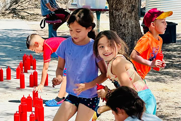 A group of girls grab ketchup bottles to squirt each other with water