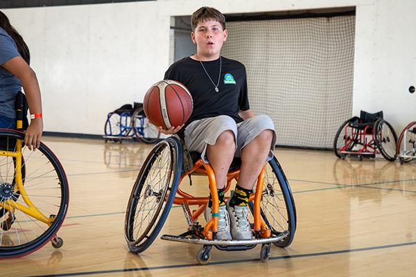 A boy in a wheelchair holds a basketball