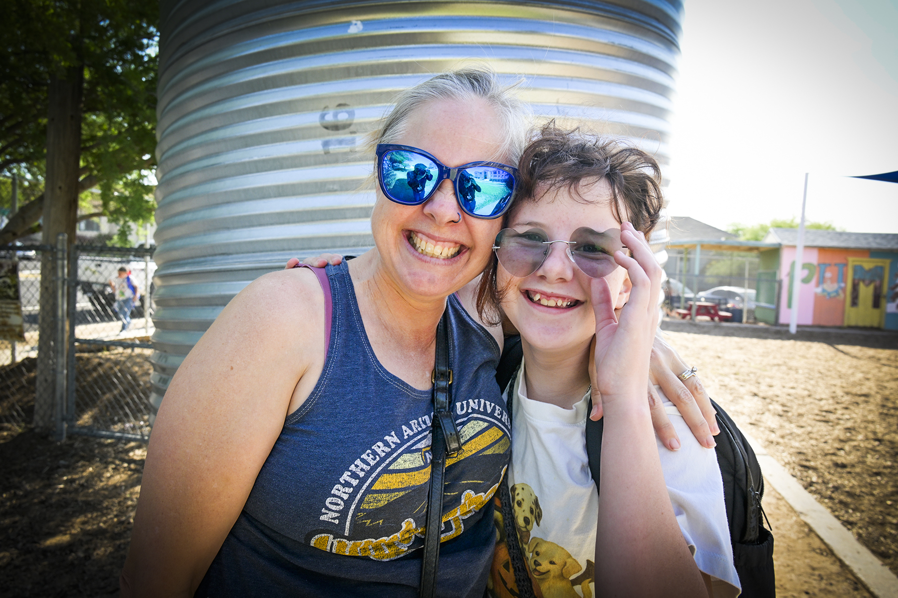 A mom and daughter smile in their sunglasses