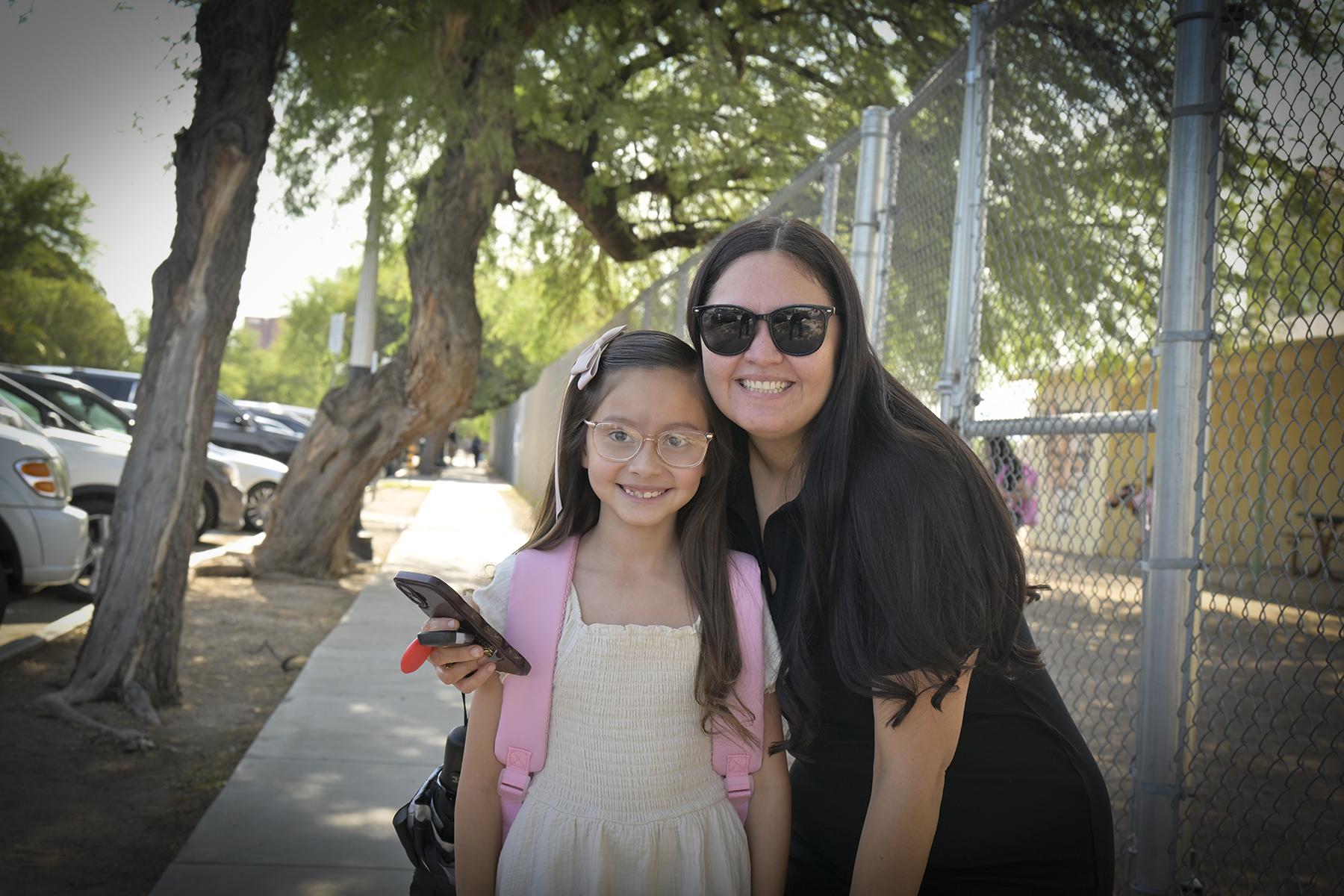 A mom and daughter smile outside school